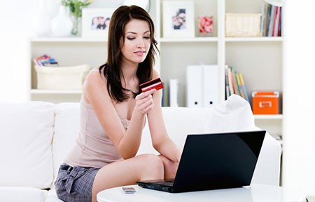 girl holding credit card in front of laptop